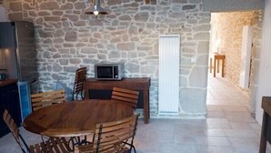 A stone-walled room with a wooden dining table and chairs, a microwave, and a small kitchen area. - Fisherman's house Gulf of Morbihan (Sarzeau)