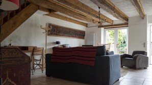 A living room with a sofa, a wooden coffee table, a red patterned rug, and a large wall tapestry. - Fisherman's house Gulf of Morbihan (Sarzeau)