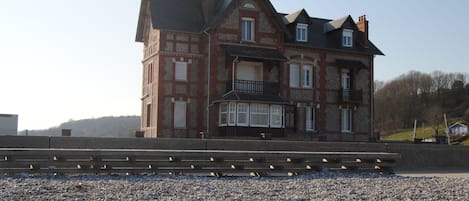 A large, multi-story house with a prominent balcony and a stone facade.