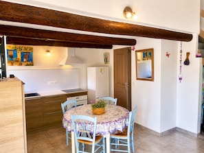 Cocina compacta con comedor, vigas de madera y una pequeña mesa con sillas.