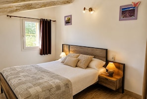 Ein Schlafzimmer mit einem Bett, Nachttischlampen, einem Fenster mit Vorhängen und einem Wandbild.
