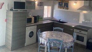 Une cuisine compacte avec un coin repas, comprenant un lave-linge, un four à micro-ondes et un petit évier.
