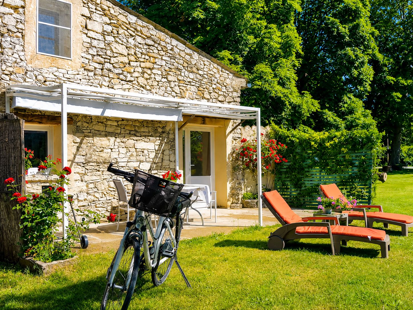 Un bâtiment en pierre doté d’un patio couvert, d’un vélo et de sièges extérieurs.
