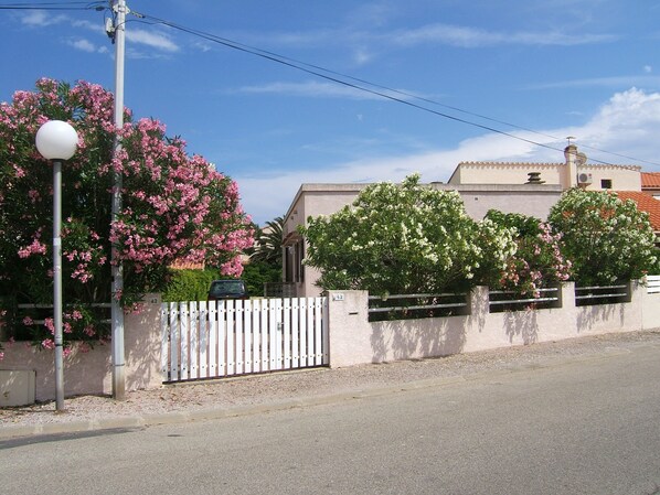 A residential street with a white fence, a street lamp, and flowering trees. - RENOVATED SINGLE HOUSE 150 meters from the beach and shops (Le Barcarès)