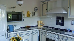 A kitchen with white cabinets, a microwave, a coffee maker, and a sink.