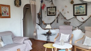 A cozy living room with a wooden floor, a sofa, a coffee table, and a decorative wall hanging.