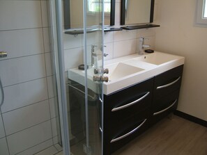 A modern bathroom with a glass shower enclosure, a white sink with a mirror above, and black cabinetry with silver handles. - RENOVATED SINGLE HOUSE 150 meters from the beach and shops (Le Barcarès)