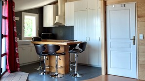 A modern kitchen with a wooden island, bar stools, and a staircase leading to an upper level. - 4 stars - High standing air conditionned apartment, heated swimming pool, Geneva (Collonges sous Salève)