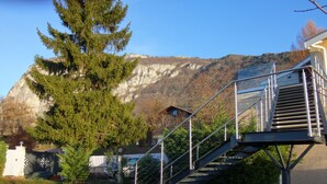 A staircase leading up to a building with a mountainous backdrop. - 4 stars - High standing air conditionned apartment, heated swimming pool, Geneva (Collonges sous Salève)