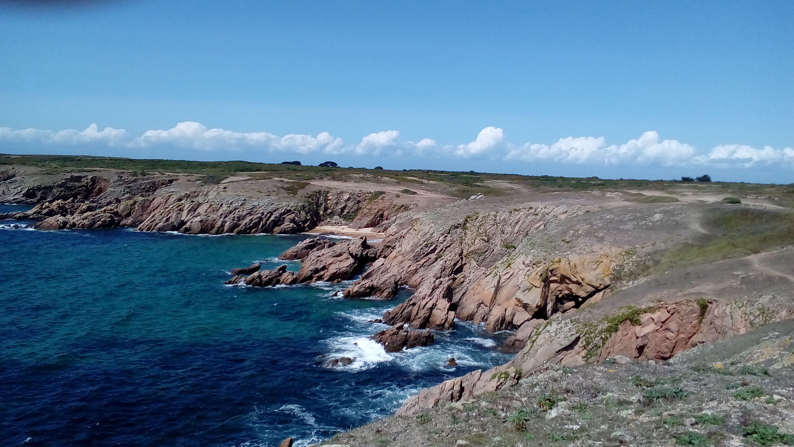 A coastal landscape with rocky cliffs and clear blue sea.