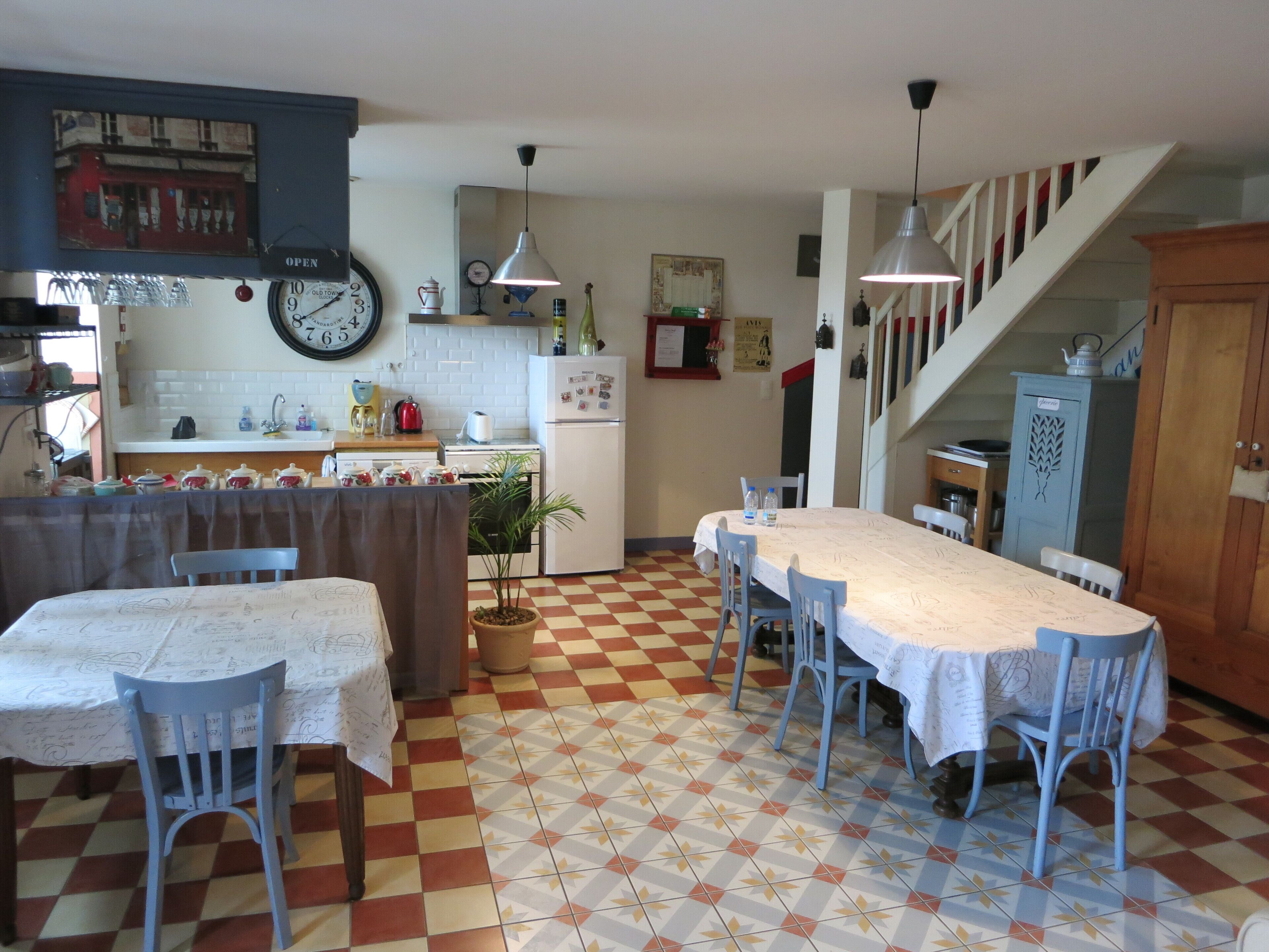 Una cuina amb rellotge, taula de menjador, cadires i escala.