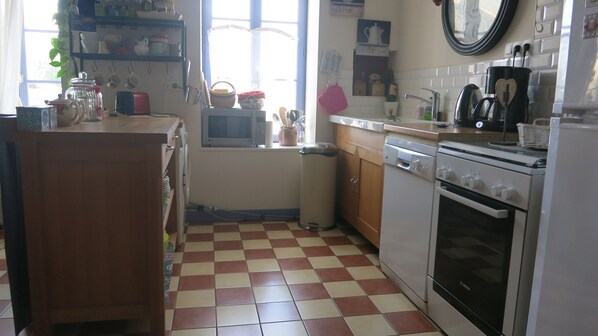A kitchen with a checkered floor, white appliances, and a window with curtains.