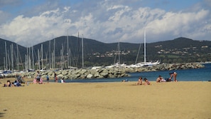 Une plage avec des gens, des bateaux et des affleurements rocheux.