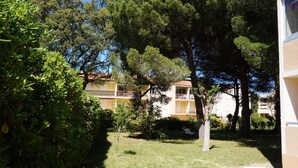 A courtyard with a grassy area, a small tree, and a building with balconies.