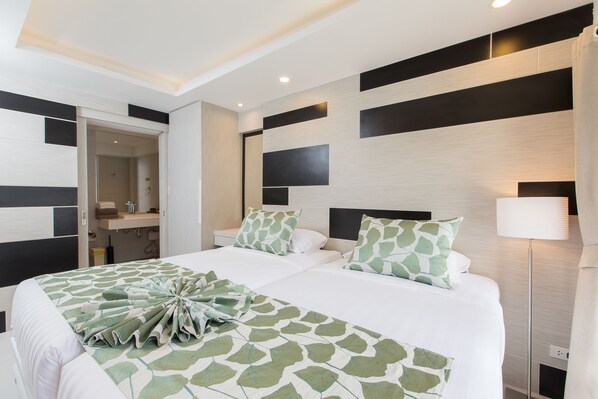 A modern hotel room with a large bed, a bedside table, a nightstand, a mirror, and a floor lamp.