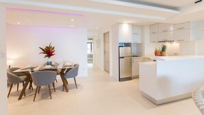 A modern kitchen with white cabinetry, a central island, and a dining area with a table and chairs. - ROMANTIC AND DESIGN APARTMENT, PATONG BEACH (PATONG)