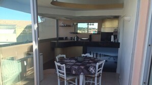 Een klein balkon met een glazen deur, een ronde tafel met stoelen en een keuken met uitzicht op de stad.