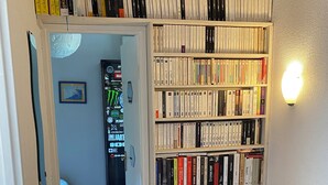 Un escalier mène à une pièce remplie de livres, où l’on aperçoit une porte et où un petit tapis est posé sur le sol.