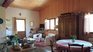 A cozy wooden cabin interior with a dining area, a sofa, a bookshelf, and a television. - Apartment / house 12 people, Pontchéry (Montaimont)