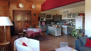 A cozy living room with a dining area, wooden walls, and a kitchen with modern appliances. - Apartment / house 12 people, Pontchéry (Montaimont)