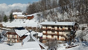 A snow-covered mountain village with traditional wooden houses, a ski lift, and a clear sky. - Apartment / house 12 people, Pontchéry (Montaimont)