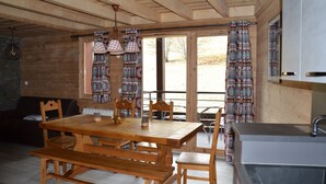 Un interior de madera con una mesa de comedor, bancos y una zona de cocina con un lavabo.