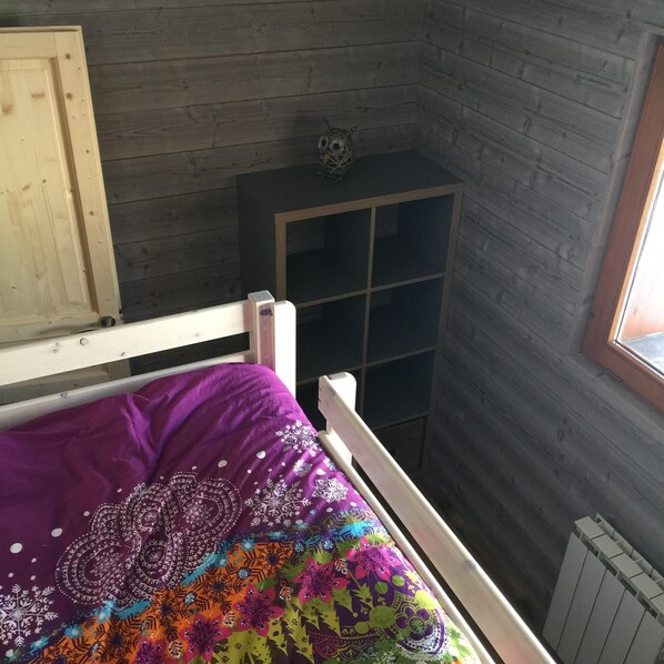 Ein Schlafzimmer mit einem Bett, einem Fenster und einem Holzschrank.