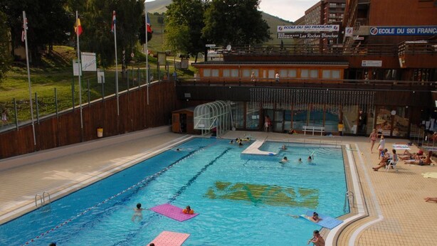 Una piscina con múltiples carriles, un trampolín y una zona cubierta.