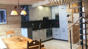 Una cocina moderna con armarios de madera, una mesa de comedor y una escalera.