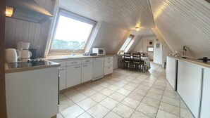 Une cuisine moderne dotée d’une grande fenêtre, d’un coin repas et d’un plafond haut avec des poutres en bois.