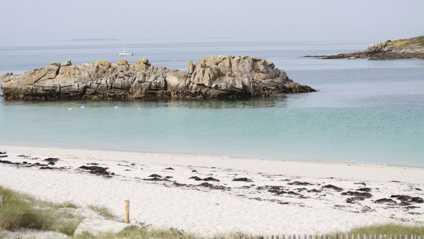 Eine felsige Küstenlinie mit klarem Wasser und einem Sandstrand.