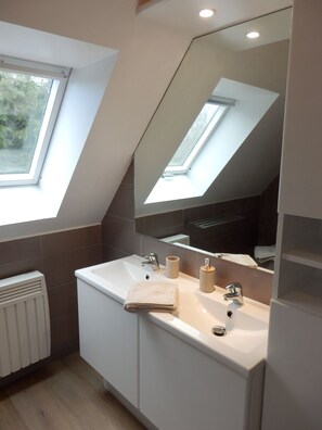Ein modernes Badezimmer mit Oberlicht, Waschbecken in Weiß und einem großen Spiegel.
