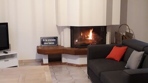 Ein Wohnzimmer mit Kamin, Fernseher und einer Couch mit Kissen.