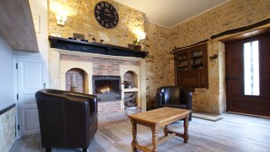 Uma sala de estar acolhedora com lareira, sofá de couro e uma mesa de madeira.