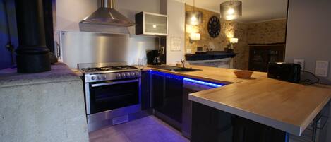 A modern kitchen with stainless steel appliances, a central island, and blue under-cabinet lighting.