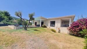 A house with a covered porch, a satellite dish, and a small garden with flowering plants. - Family villa with swimming pool, between sea and mountains. (Prunelli-di-Fiumorbo)