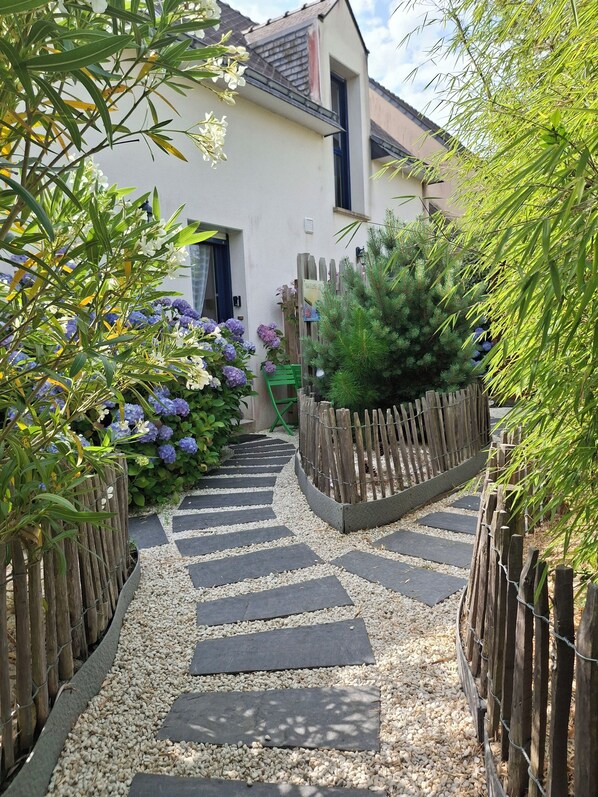 A garden pathway leading to a house with a wooden fence and a sign that reads "Nature's Way".