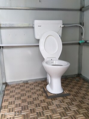 Ein kleines, sauberes Badezimmer mit einer weißen Toilette, einem sichtbaren Tank und einem Musterboden.