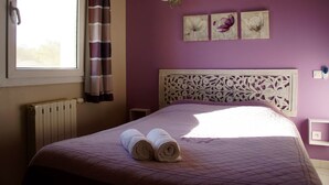 A bedroom with a purple wall, a white headboard with floral patterns, and three wall-mounted lamps. - Apartment in the heart of Vaucluse close to the tourist attractions of Vaucluse (Loriol du Comtat)