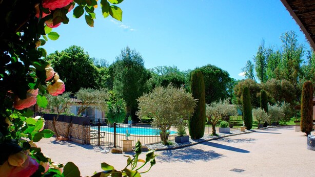 A pool area with a fence, surrounded by various trees and plants. - Apartment in the heart of Vaucluse close to the tourist attractions of Vaucluse (Loriol du Comtat)
