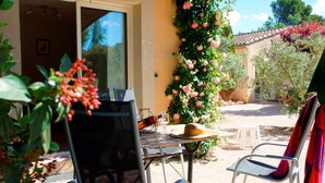 An outdoor patio with a table and chairs, a bottle, and a hat. - Apartment in the heart of Vaucluse close to the tourist attractions of Vaucluse (Loriol du Comtat)