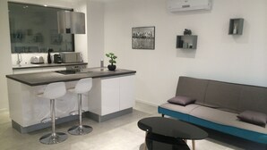 A modern kitchen with a bar area, a sofa, and a small table.