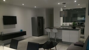 A modern kitchen with a built-in refrigerator, a dining area with a table and chairs, and a living area with a sofa.