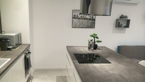 A modern kitchen with a central island, a built-in oven, and a stainless steel range hood.