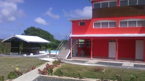 A two-story building with a red exterior, a covered patio area, and a staircase leading to the upper floor.