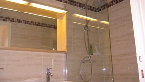 Un baño con ducha de vidrio, un espejo y un lavabo.