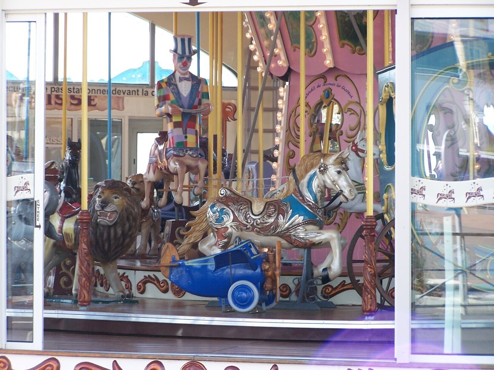 A carousel with colorful horses and a blue car.