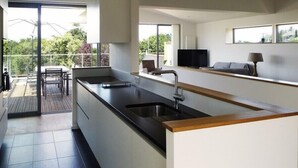 A modern kitchen with a large island, a dining area with a table and chairs, and a living area with a sofa and TV. - Kervegan magnifique villa vue mer à Pleumeur Bodou (PLEUMEUR BODOU)
