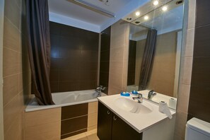 Une salle de bain moderne avec une baignoire, un lavabo et un grand miroir.