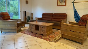 A cozy living room with a wooden sofa, a wooden coffee table, and a hammock. - Beautiful, quiet property with swimming pool, spa and stone outbuilding + air conditioning (Privas)